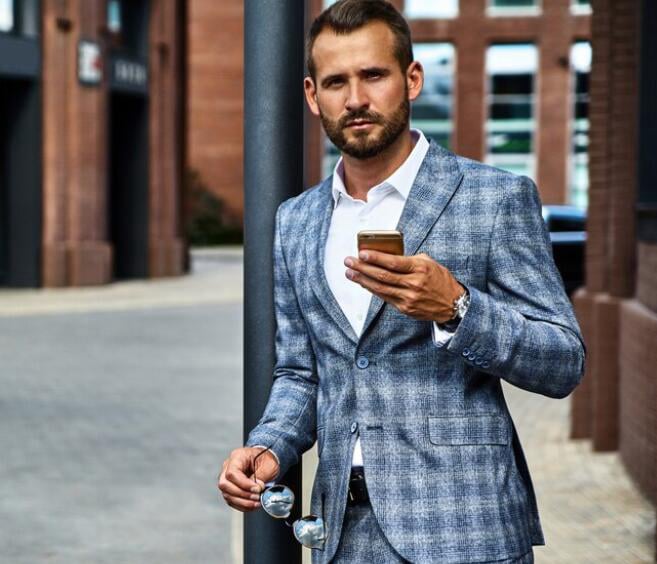 Businessman checking his phone on a city street, reflecting habits like direct communication and planning ahead